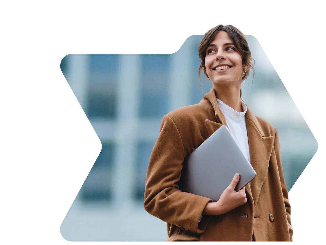 Woman in brown coat smiling and holding a laptop with a birthday discount notification from OWLCLOTHES